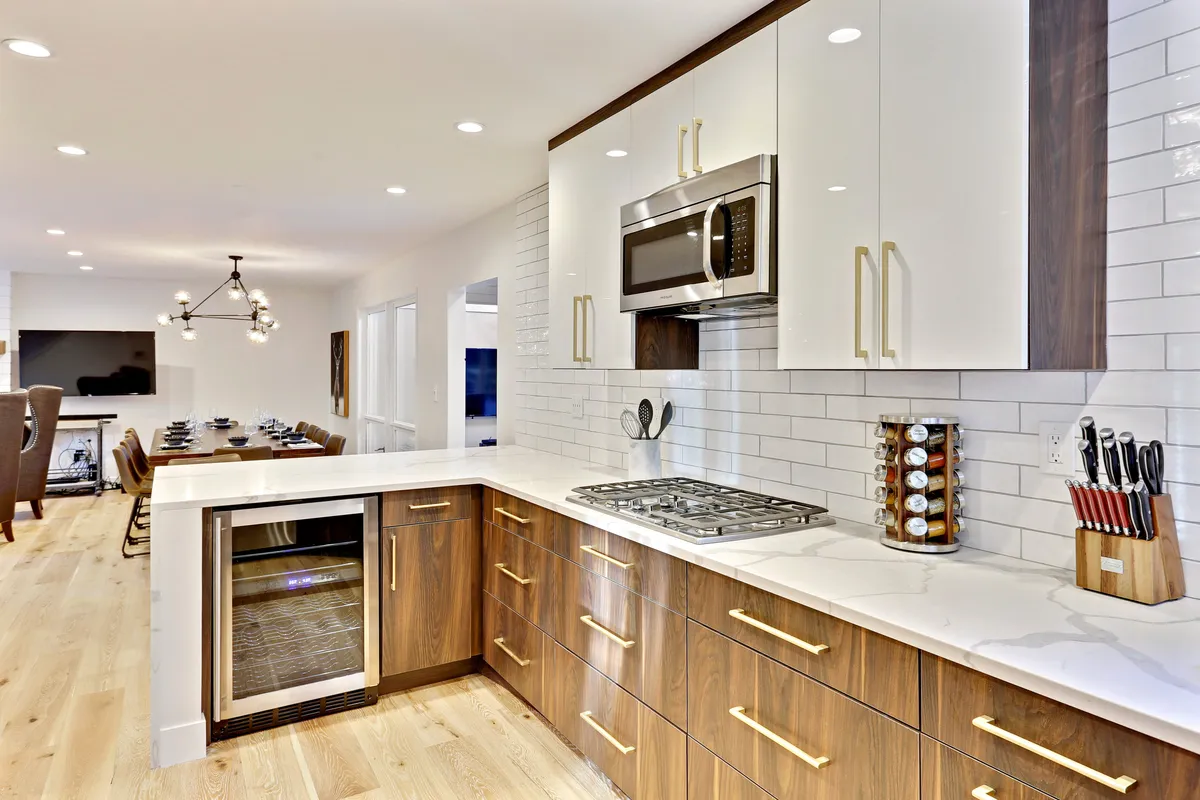 A contemporary chef’s kitchen featuring a spacious island, stainless steel appliances, sleek gold hardware, and white cabinetry, all basked in natural light. The kitchen is clearly designed for both cooking and entertaining, offering a welcoming atmosphere where meals and conversations come alive.