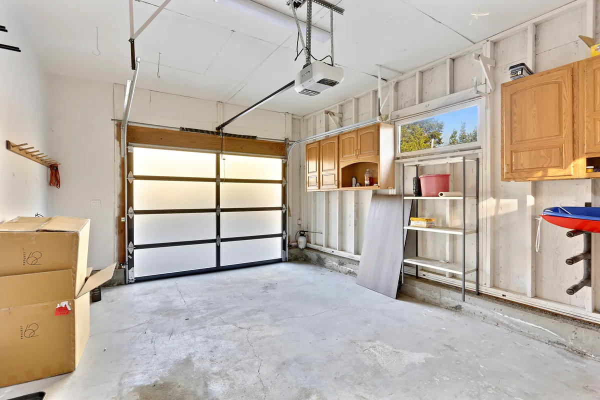 An organized garage with a visible garage door, shelving units, and storage boxes, set up for storing gear and outdoor equipment. The practical space is clean and ready for adventure prep or safe stowing of seasonal gear.