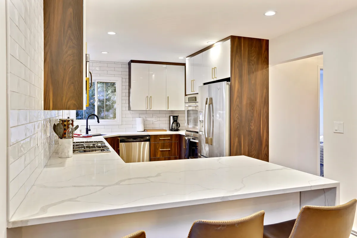 A bright, modern kitchen with a central island, modern appliances, white cabinetry, and wood accents. The layout invites both cooking and casual dining, with thoughtful touches that make group gatherings easy and enjoyable.